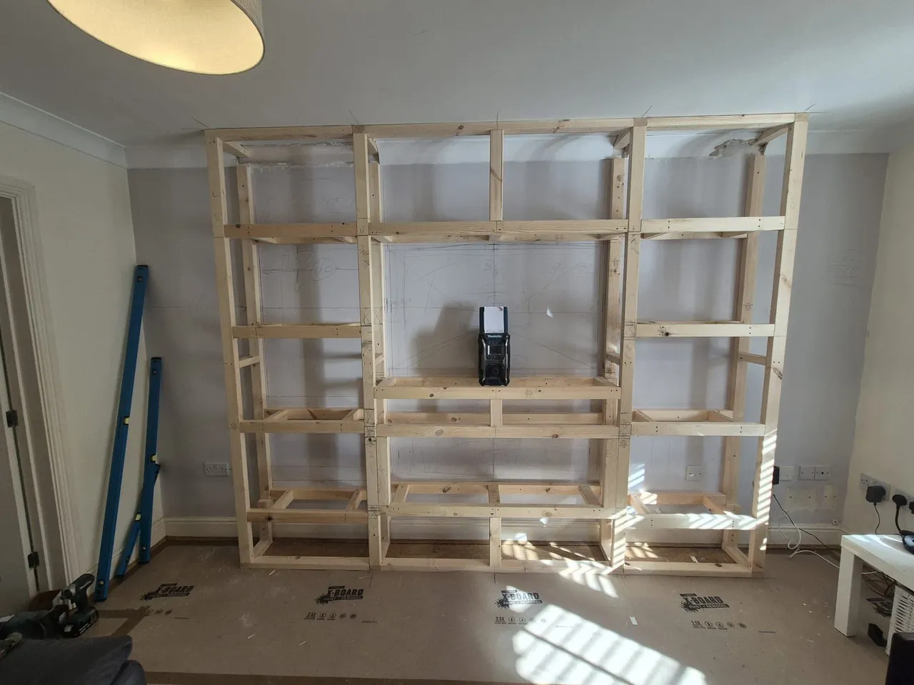 Timber frame for a media wall set out across a living room wall