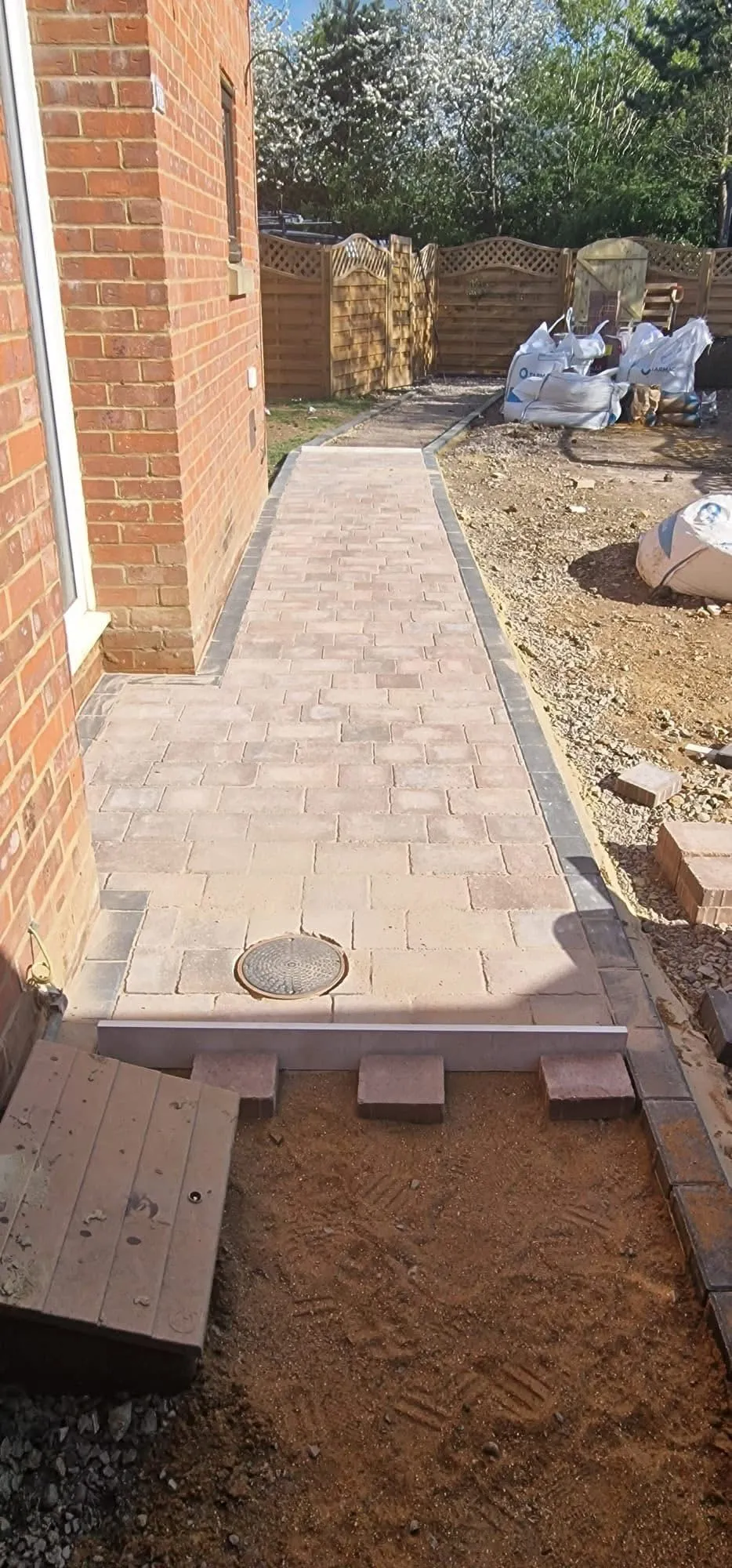 A completed block paved driveway and path in Milton Keynes with kerb edging and a fitted inspection cover
