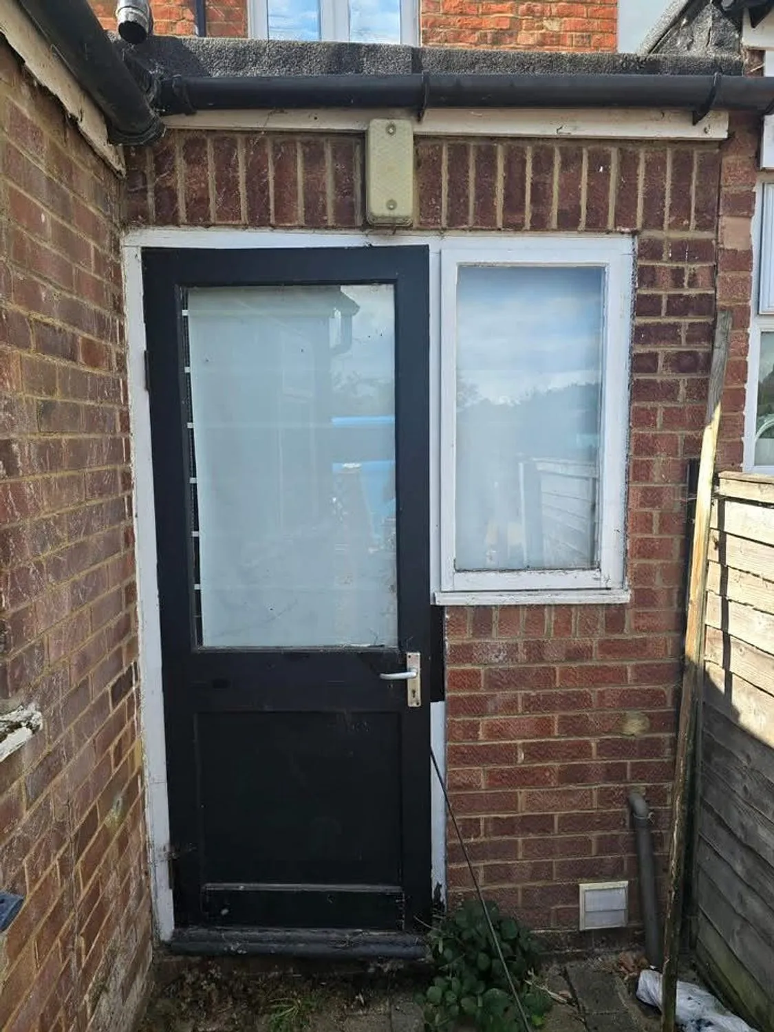 Failed rear door and side window in a brick wall before replacement