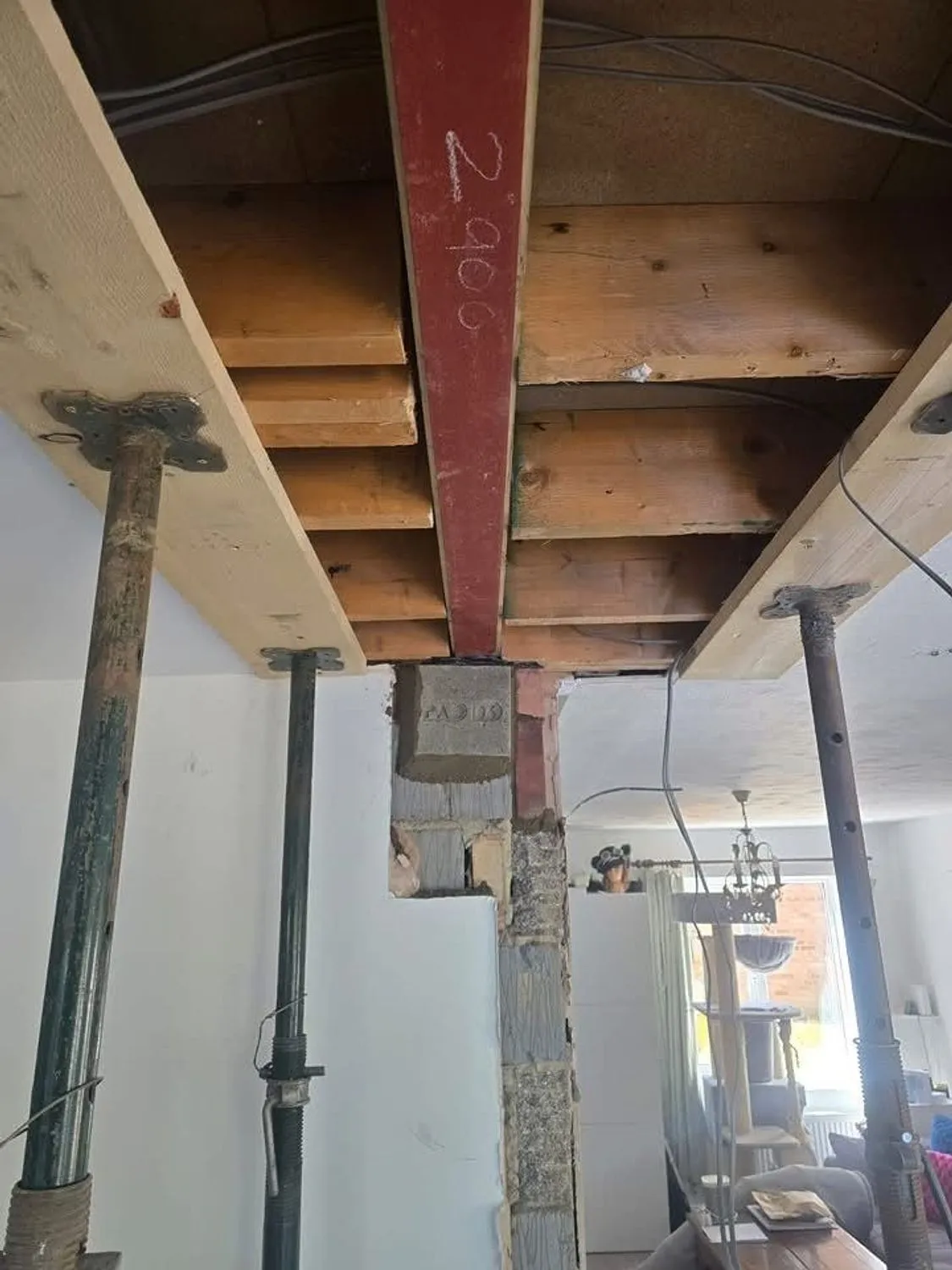 Steel beam installed under existing floor joists with padstones and props still in place