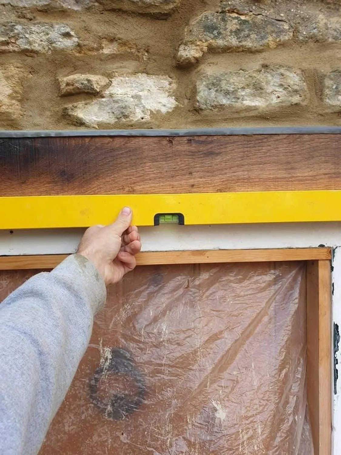 New oak lintel levelled into a stone opening during structural repair